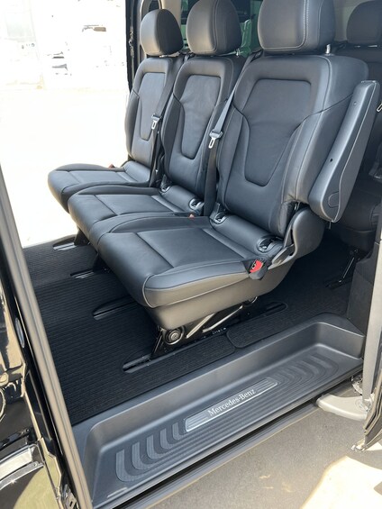 Un habitacle de véhicule avec des sièges en cuir noir, une console centrale et le logo Mercedes-Benz sur le tapis de sol. 2