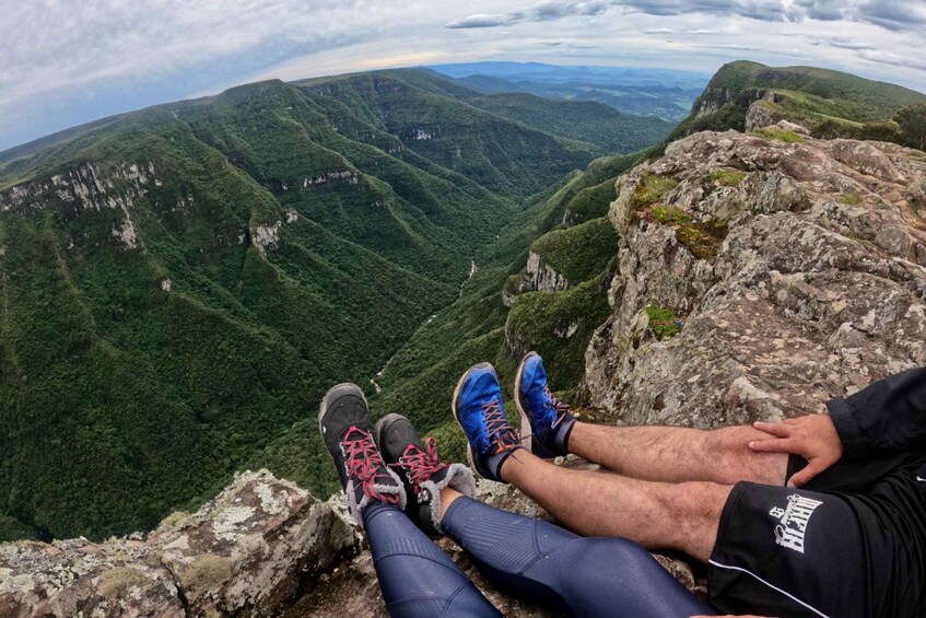Une personne assise sur un promontoire rocheux, d’où elle domine un paysage montagneux. 3
