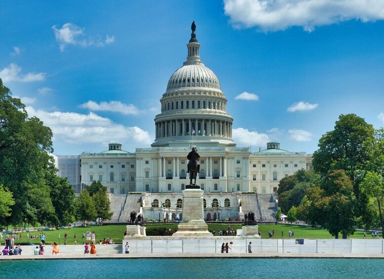 El edificio del Capitolio de los Estados Unidos con un cielo azul despejado y una estatua al frente. 1