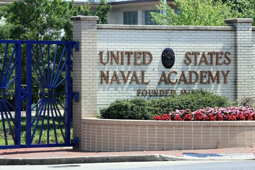 Letrero de la Academia Naval de los Estados Unidos, con una puerta azul y flores rojas al frente. 3