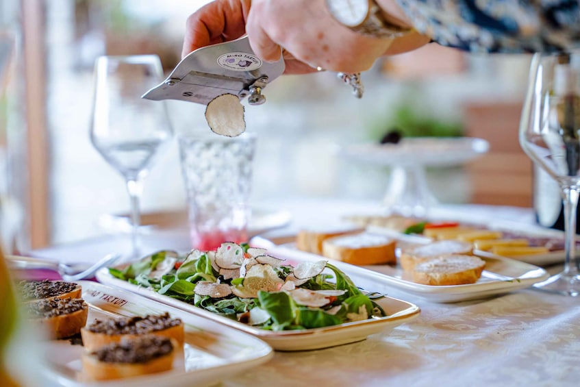 A person using a tool to slice a food item, likely a tart, on a plate with a salad. 5