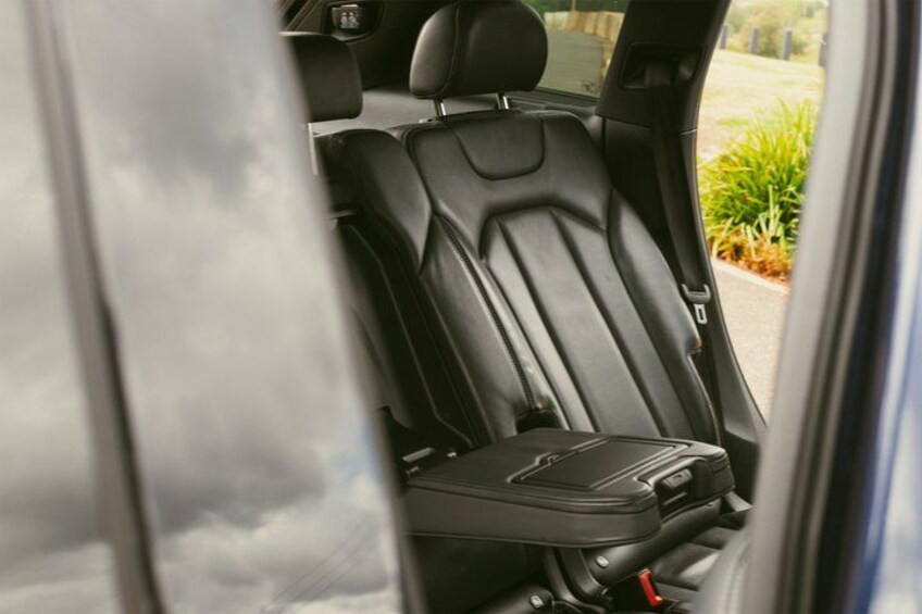 A car's interior with a black leather seat and a black seat cover. 4