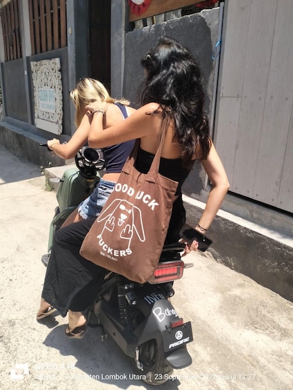 Two women riding a motorcycle on a street. 4