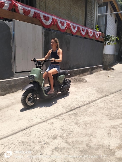 A person riding a green scooter on a concrete street. 2