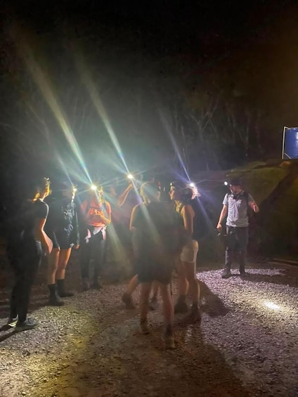 A group of people in a dimly lit outdoor setting with spotlights. 3