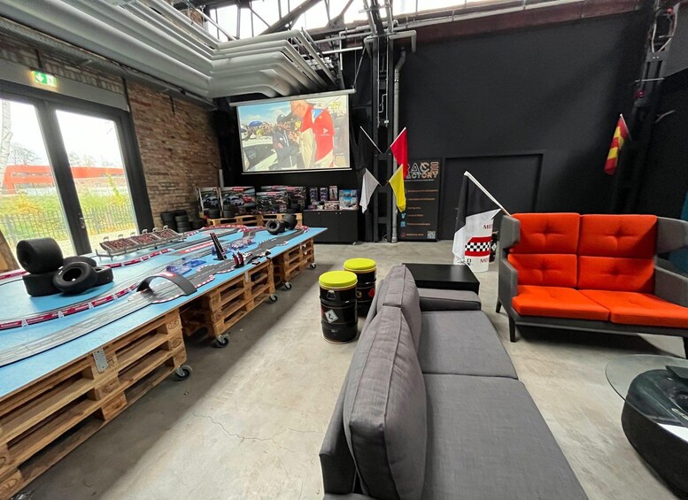 A room with a racing simulator setup, a large screen, and a racing flag. 5