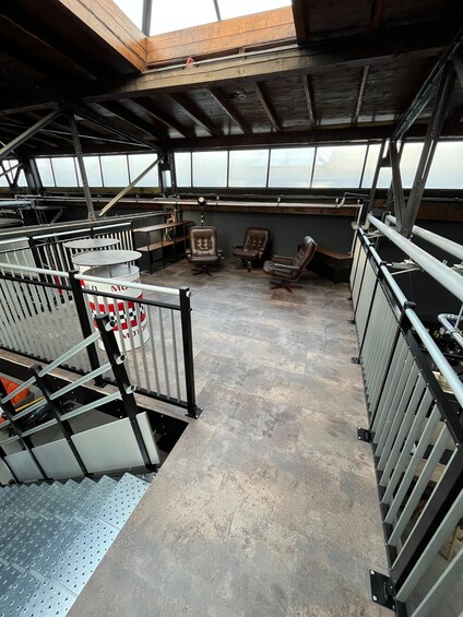 A covered outdoor area with metal railings, seating, and a concrete floor. 3