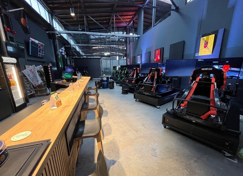 A racing simulator setup with multiple racing seats and screens. 1