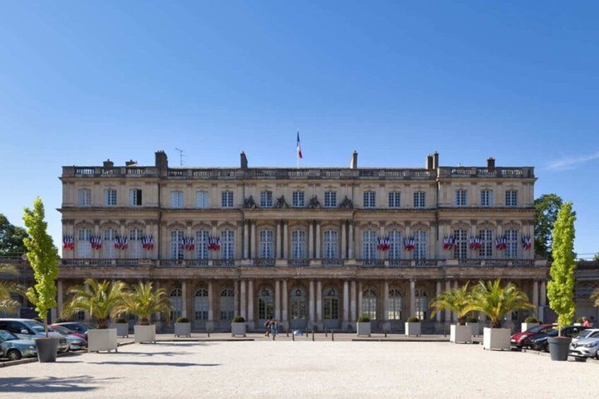 A large, historic building with multiple stories and a symmetrical facade, featuring a central entrance and decorative elements. 3