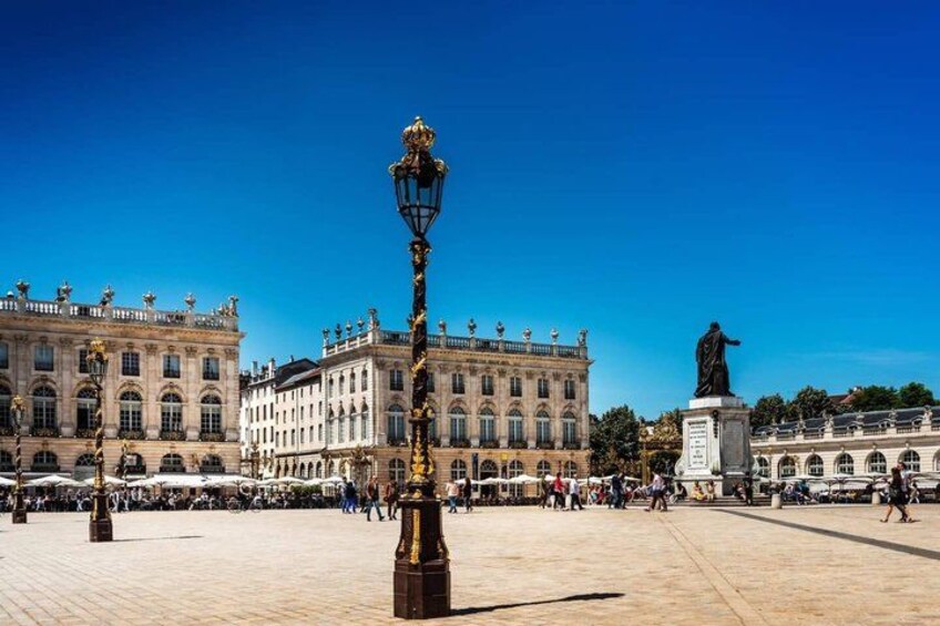 A plaza with a statue, a lamppost, and historic buildings. 5