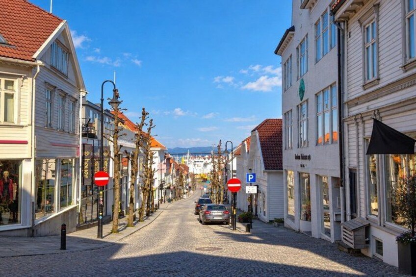 A cobblestone street lined with white buildings, a parked car, and a no entry sign. 3