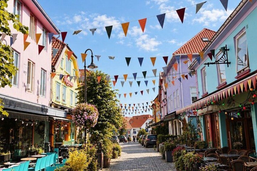 A colorful street with buildings, outdoor seating, and triangular flags. 5
