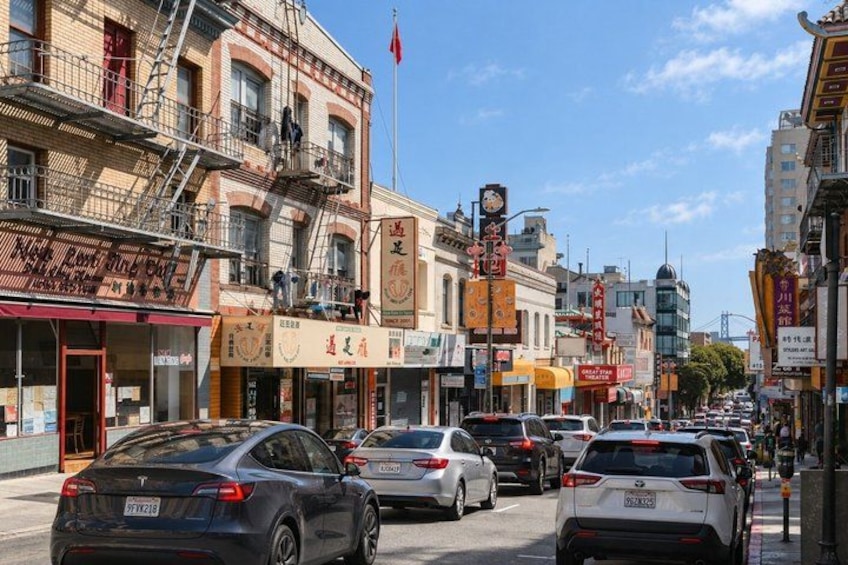 A busy urban street with cars, buildings, and storefronts. 5