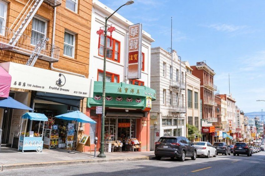 A street lined with shops, including a fruit stand and a restaurant. 4