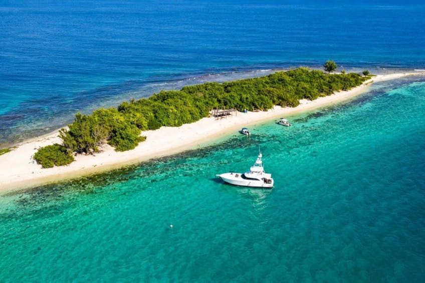 A white yacht anchored near a tropical island with clear turquoise waters and a sandy beach. 1