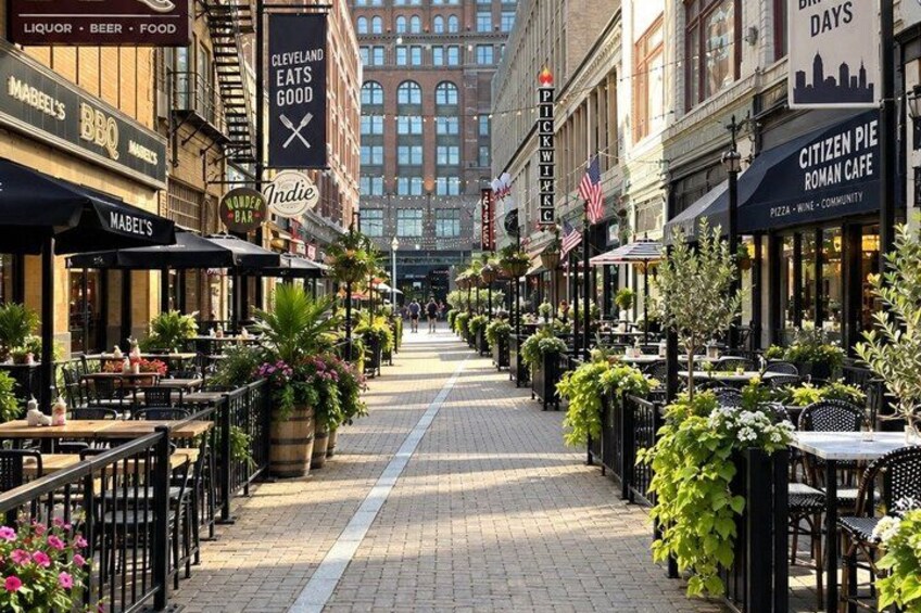 A street lined with outdoor cafes, potted plants, and American flags. 5