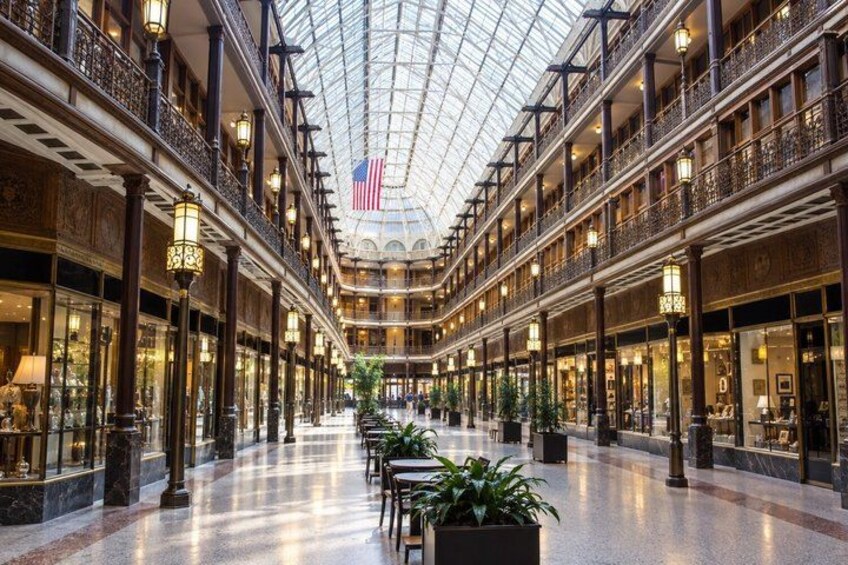A spacious indoor shopping mall with multiple levels, ornate railings, and a glass ceiling. 2