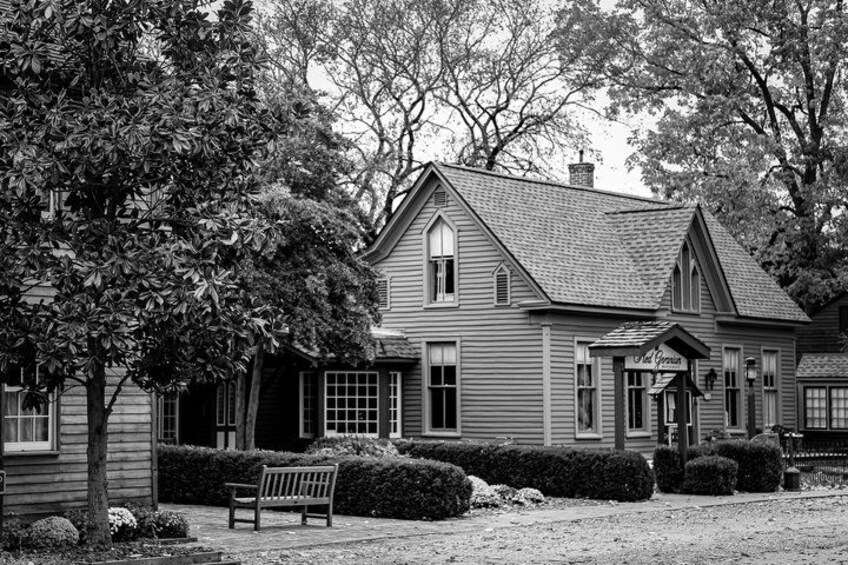 A two-story house with a gabled roof, a front porch, and a bench in the yard. 4