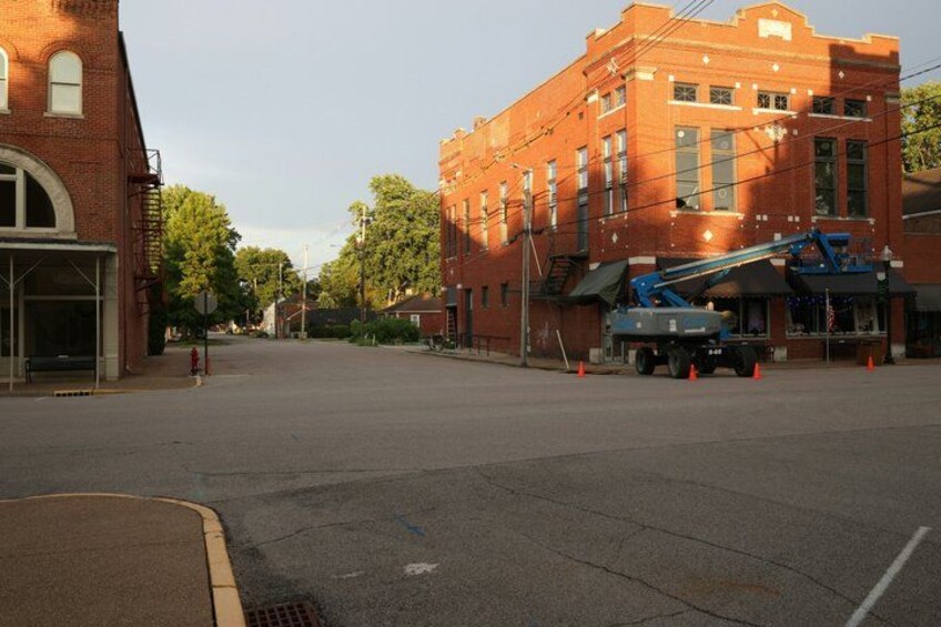 A street with a brick building, a blue crane, and a parked truck. 3