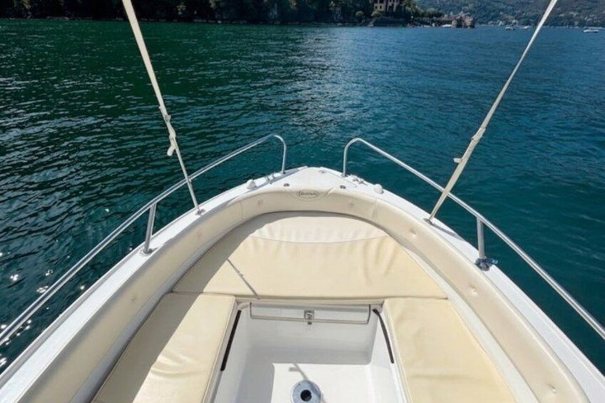 A boat's interior with a cushioned seating area and a steering wheel. 2