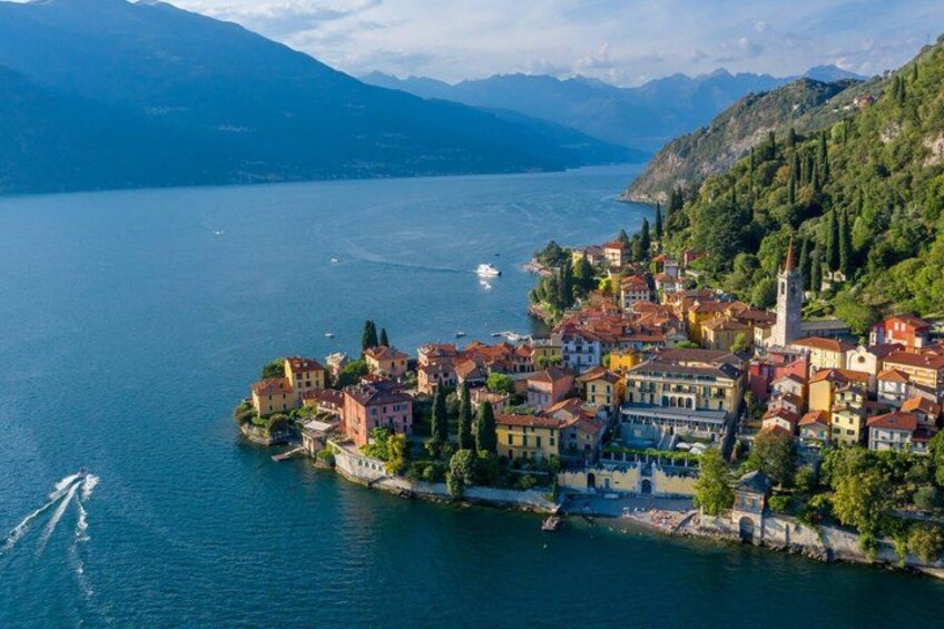 A lakeside town with colorful buildings, a church, and mountains in the background. 3