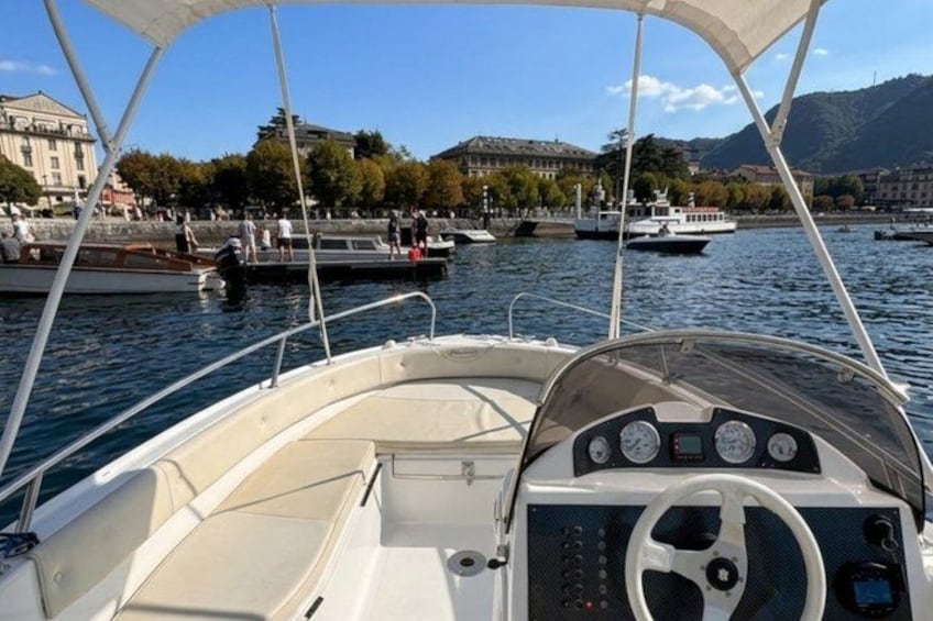 A boat's interior with a steering wheel, dashboard, and canopy. 1