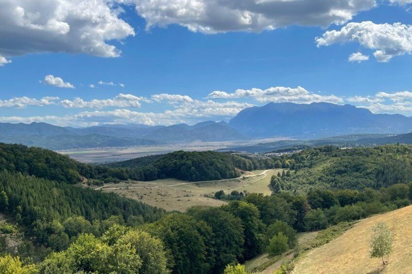 A mountainous landscape with dense forests, a clear sky, and distant mountains. 2