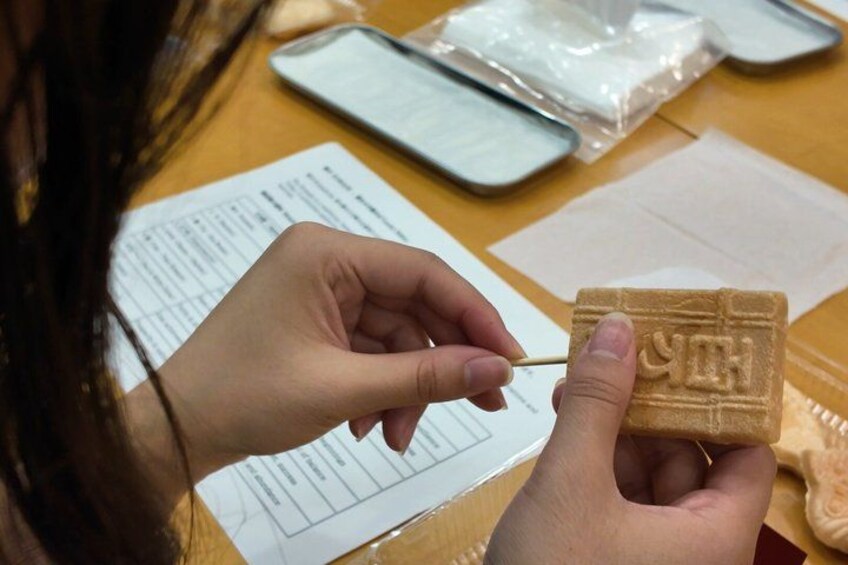 A person holding a chocolate bar with a toothpick. 3