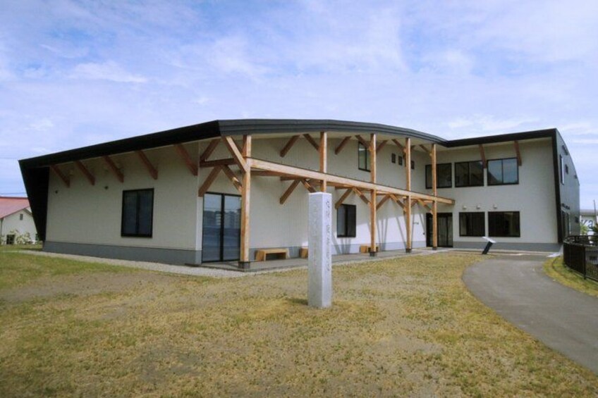 A modern building with a curved roof, wooden beams, and large windows. 2