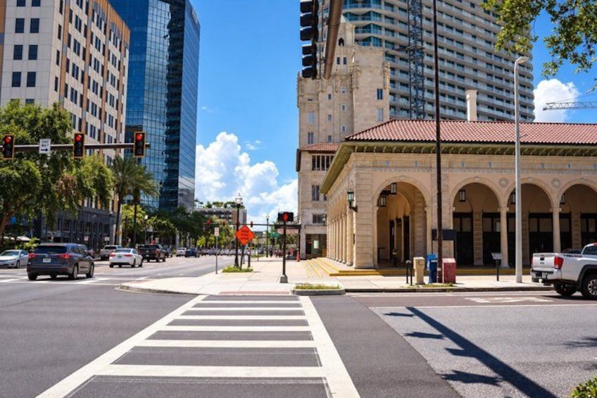 A city intersection with traffic lights, a pedestrian crosswalk, and buildings including a modern skyscraper and a historic building with arches. 3