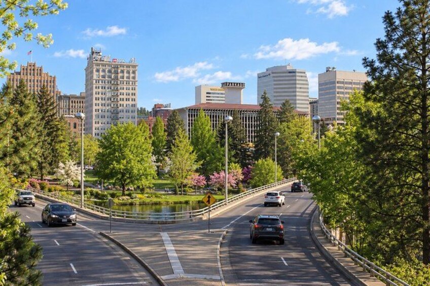 A multi-lane road with cars, a pedestrian bridge, and buildings in the background. 3