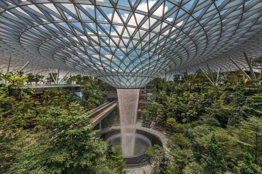 A modern architectural structure with a glass dome and a central water feature surrounded by lush greenery. 3