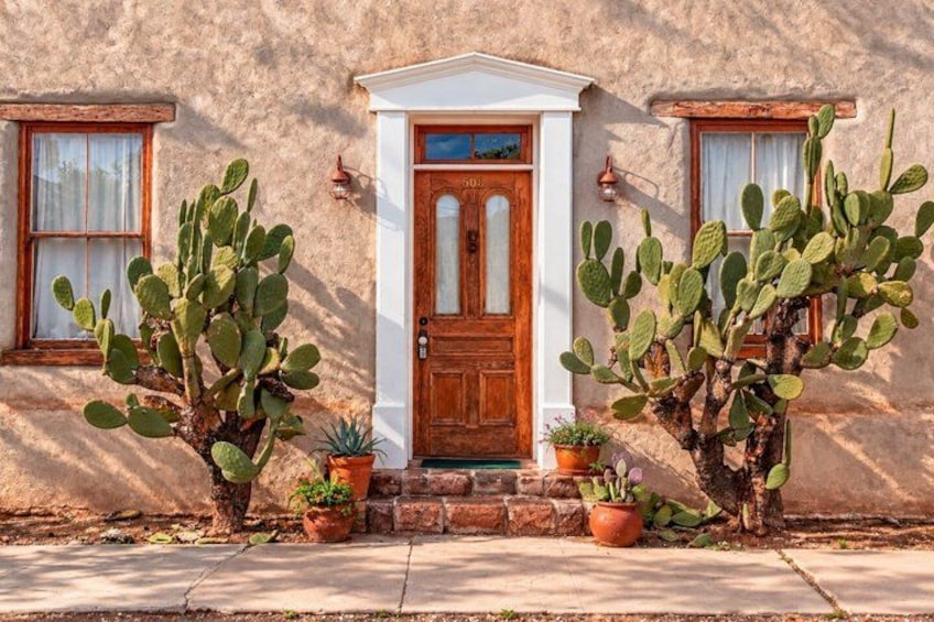 A building with a wooden door, windows, and potted plants. 4