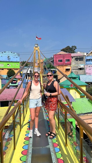 Two people walking on a colorful pedestrian bridge with a flag in the background. 1