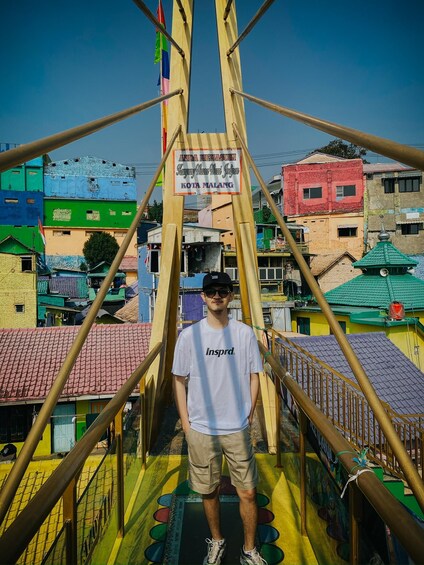 A person standing on a bridge with colorful buildings in the background. 3