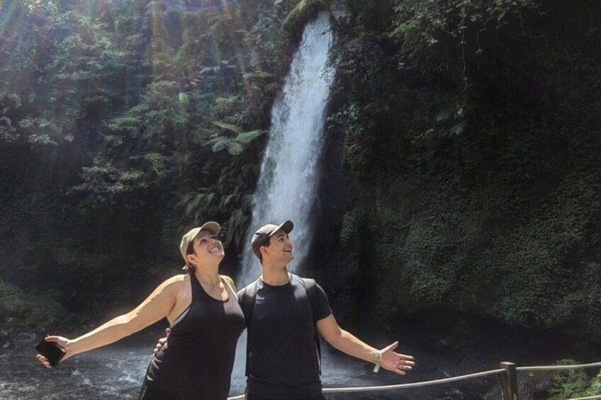 A waterfall with a couple standing in front of it. 1