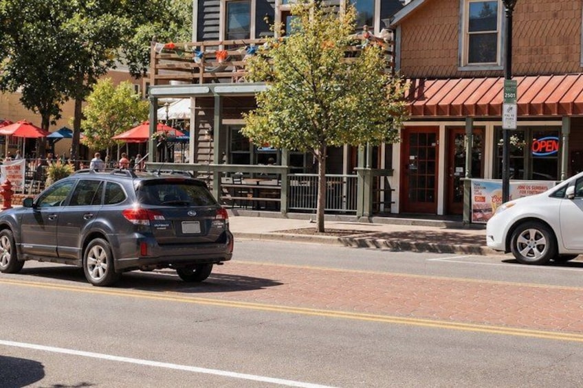 A street with cars, a building with a red awning, and a tree. 4