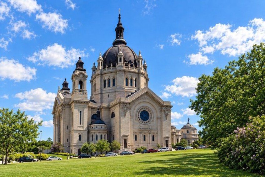 A large historic church with multiple domes and towers, surrounded by a well-maintained lawn and trees. 1