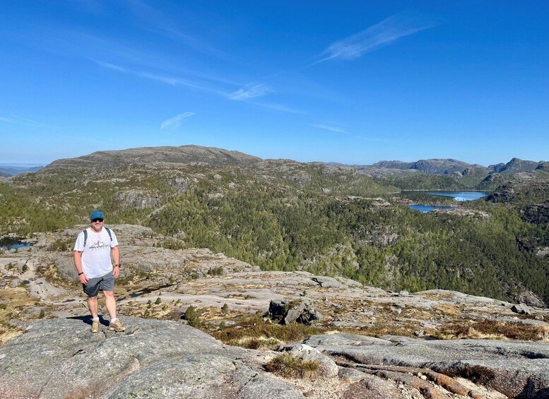 A person standing on a rocky outcrop with a mountainous landscape and a lake in the background. 2