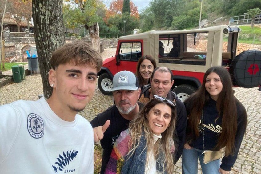 A group of people posing in front of a red and beige off-road vehicle. 2