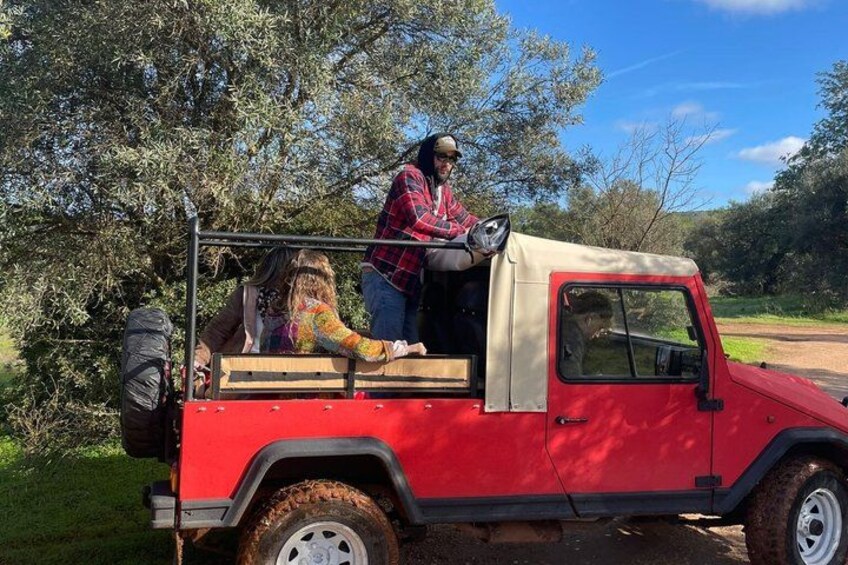 A red off-road vehicle with a beige roof parked on a dirt road. 4