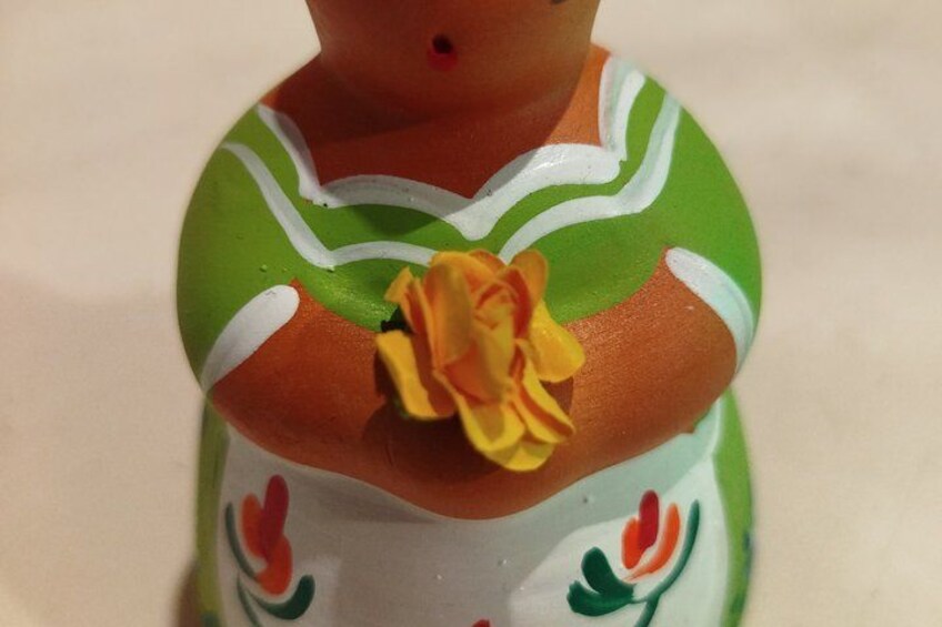 A ceramic figurine with a green and white dress, a yellow flower, and red and green floral patterns. 4