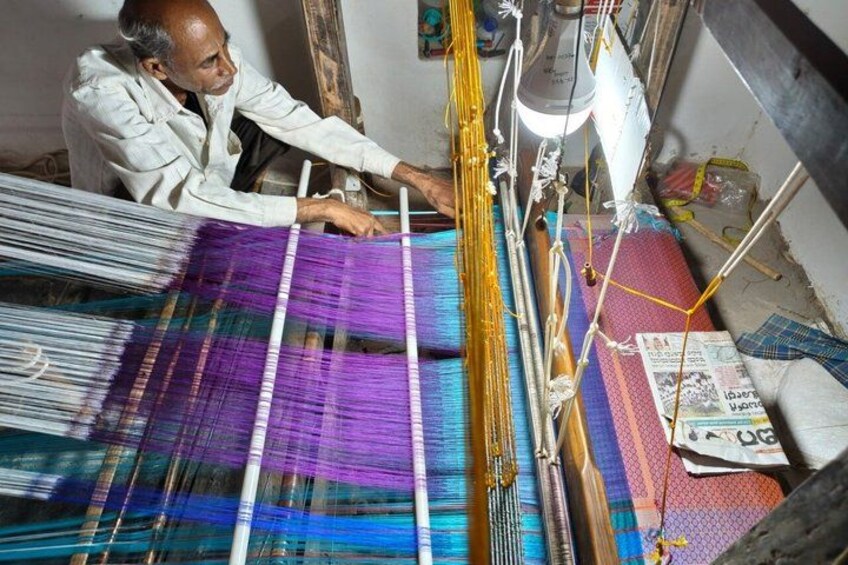 A person weaving on a loom with colorful threads. 1