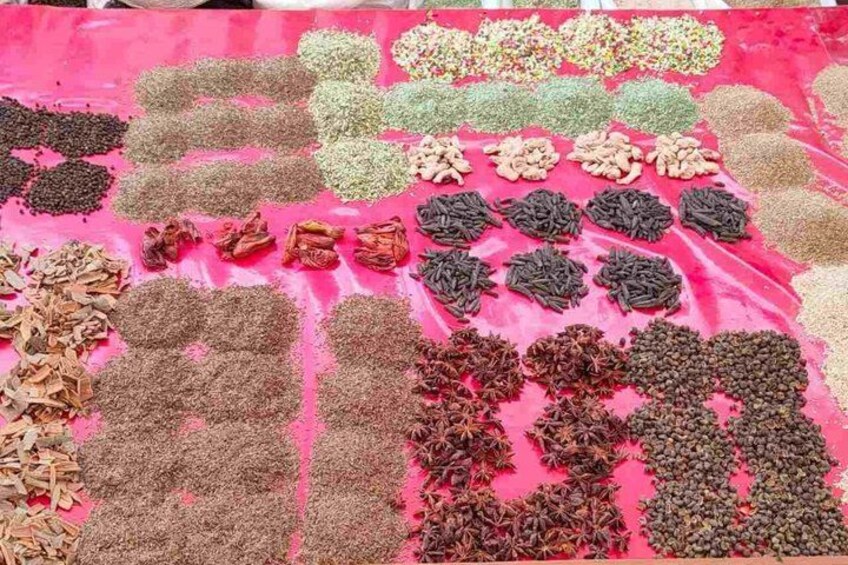 A variety of spices spread out on a pink cloth. 3