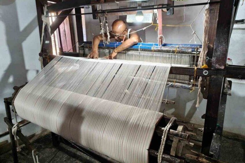 A person operating a loom with a large woven fabric. 5