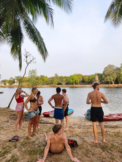 A group of people by a lake with boats and palm trees. 4