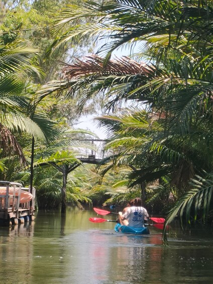 A river surrounded by palm trees, kayaks, and a boat. 2