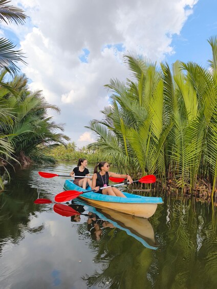 Two people kayaking on a calm river surrounded by lush greenery. 3