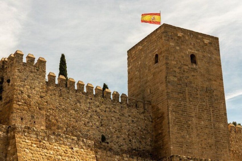 A historic stone wall with crenellations and a flag on top. 4