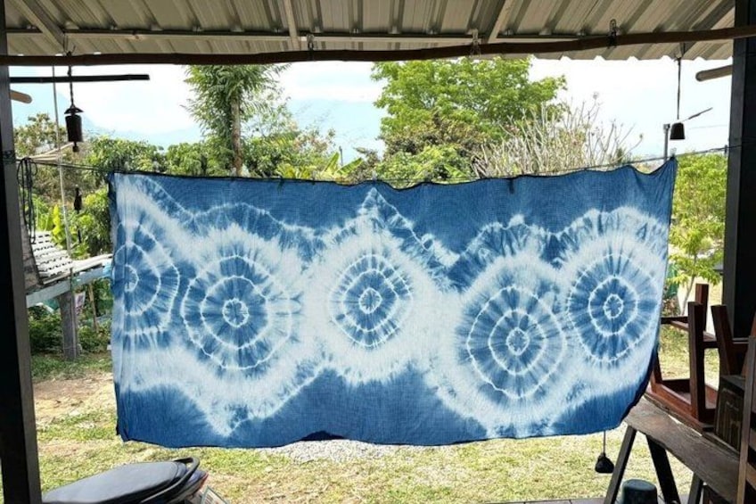 A blue and white tie-dye cloth hanging outdoors. 2